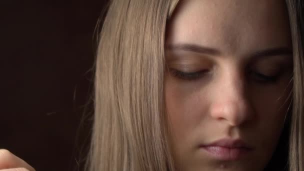 Egy gyönyörű fiatal nő arca, amint a haja a füle mögött simul. — Stock videók