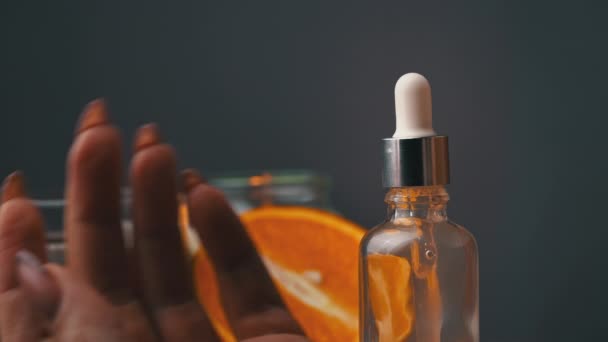 Etherische olie druppelt van een pipet in een fles op de achtergrond van een kaars — Stockvideo