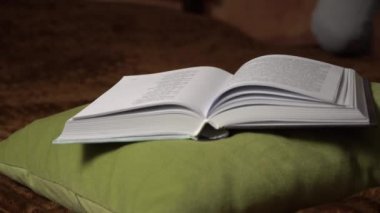 Güzel kız yatakta yatarken rahatça kitap okur.