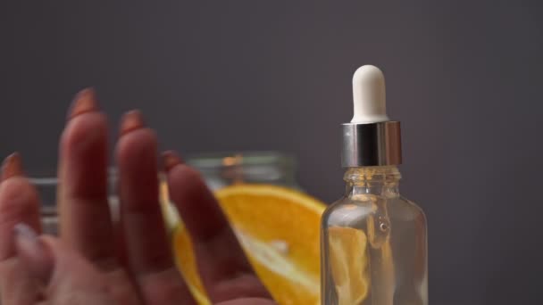 El aceite esencial gotea de una pipeta en una botella sobre el fondo de una vela — Vídeos de Stock