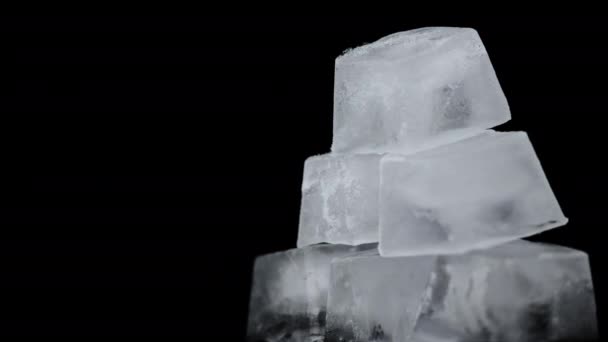 Cubos de hielo cuadrados giran sobre un fondo negro — Vídeo de stock