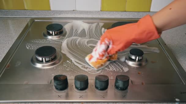 Домохозяйка в перчатках моет газовую плиту на кухне с мочалкой и пеной — стоковое видео