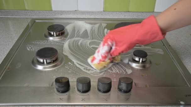 Eldivenli ev hanımı mutfaktaki gaz sobasını bez ve köpükle yıkıyor. — Stok video