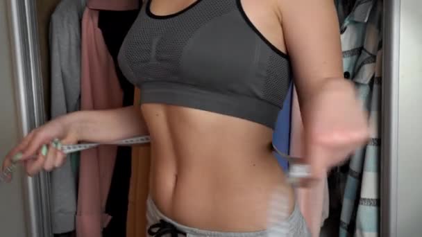 Menina com uma bela figura mede a cintura com uma fita métrica — Vídeo de Stock