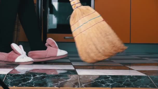 Chica joven barre el piso en la cocina con un escoba ordinario — Vídeos de Stock