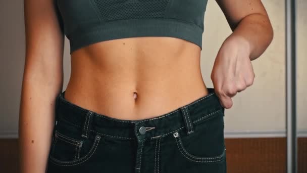 Mädchen mit schöner Figur misst alte dicke Jeans und überprüft das Ergebnis — Stockvideo