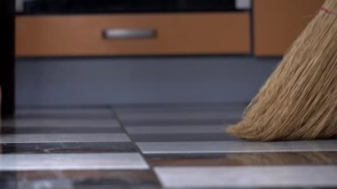 Genç kız mutfaktaki yerleri süpürüyor sıradan bir süpürgeyle