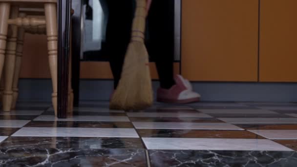 Jong meisje veegt de vloer in de keuken met een gewone bezem in slow mo — Stockvideo
