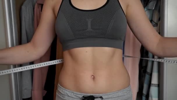 Chica con una hermosa figura mide su cintura con una cinta métrica — Vídeo de stock