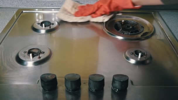 Женщина в перчатках стирает и протирает газовую плиту детергентом, пока она не засияет — стоковое видео