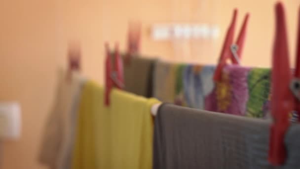 Wäsche wird auf einem Seil mit roten Wäscheklammern unter den Sonnenstrahlen getrocknet — Stockvideo