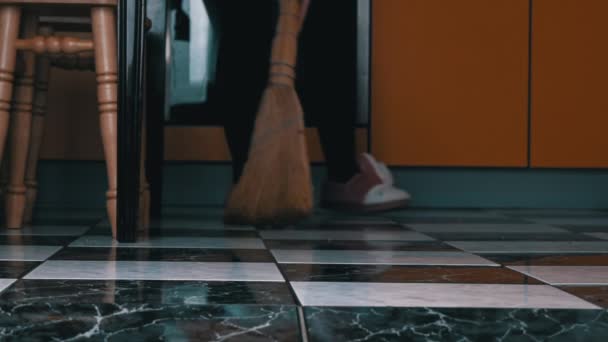Jong meisje veegt de vloer in de keuken met een gewone bezem in slow mo — Stockvideo