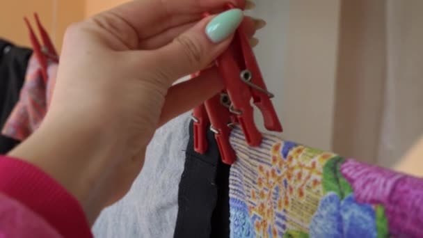 Wasgoed worden gedroogd op een touw met rode wasknijpers onder de stralen van de zon — Stockvideo