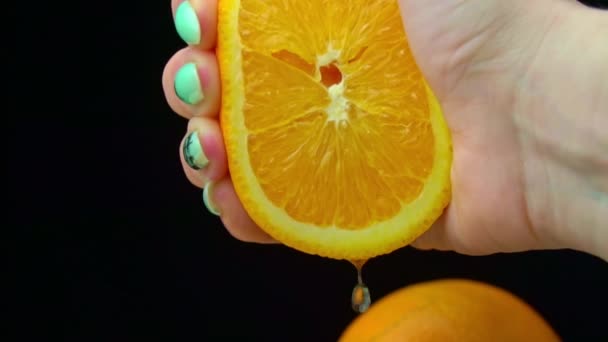 Frauenhand presst frischen Saft aus einer Orange in Slow Mo auf schwarzem Hintergrund — Stockvideo