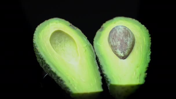 Due metà di un avocado ruotano in un cerchio su sfondo nero — Video Stock