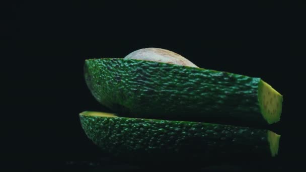 在黑色背景的圆圈中旋转的鳄梨的两半 — 图库视频影像