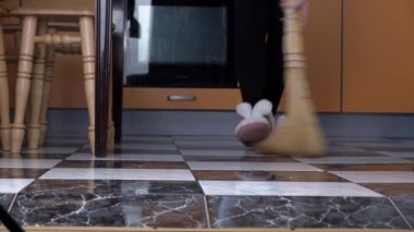 Genç kız mutfaktaki yerleri süpürüyor sıradan bir süpürgeyle