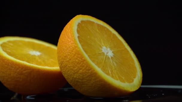 Fél lédús narancs forog egy kört a fekete háttér — Stock videók