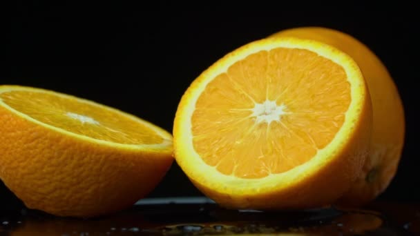 A água derrama em uma laranja brilhante suculenta em Slow Mo em um fundo preto — Vídeo de Stock