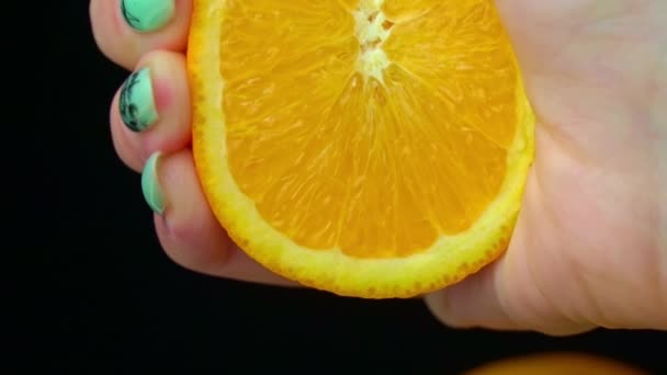 Womans Hand exprime jugo fresco de una naranja en Slow Mo sobre fondo negro — Vídeos de Stock