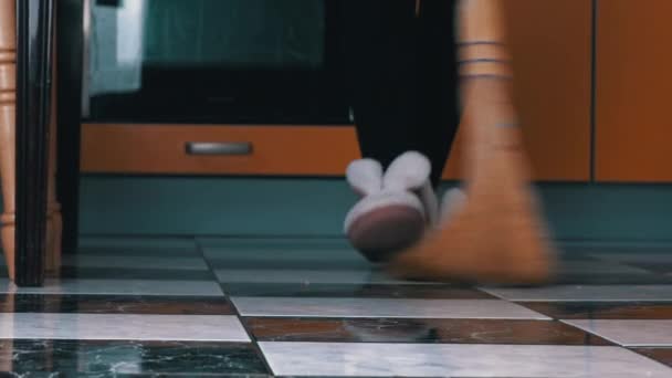 Mladá dívka zametá podlahu v kuchyni s obyčejným koštětem v pomalé Mo — Stock video