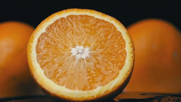 Вода льется на сочный ярко-оранжевый в медленном темпе на черном фоне — стоковое видео