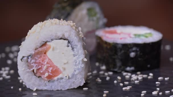 Rollo de sushi fresco con sésamo se toma con palillos especiales japoneses — Vídeos de Stock