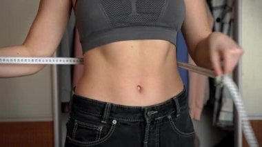 Güzel vücutlu bir kız Koca Kot pantolon giyer ve belini ölçer