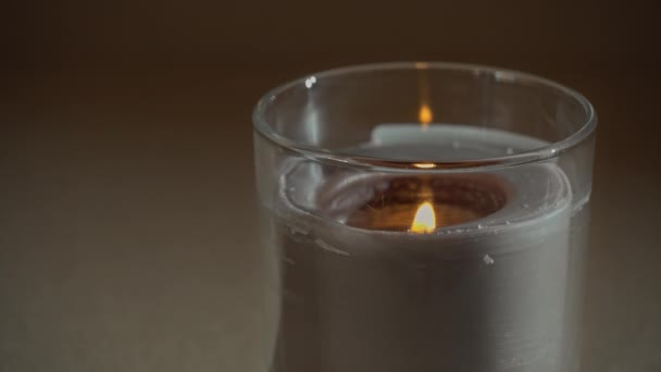 Atmosféricamente, una vela arde, emitiendo su propia sombra en la noche — Vídeo de stock