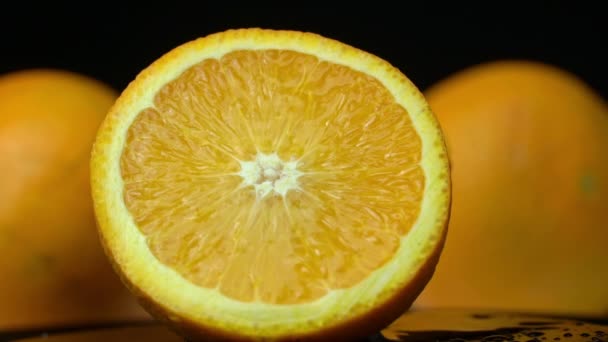 Vatten häller på en saftig ljus apelsin i långsam Mo på en svart bakgrund — Stockvideo