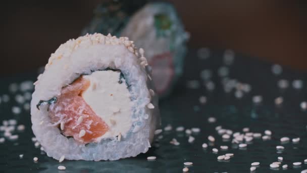 Rotolo di sushi fresco con sesamo è posizionato con bacchette giapponesi speciali — Video Stock