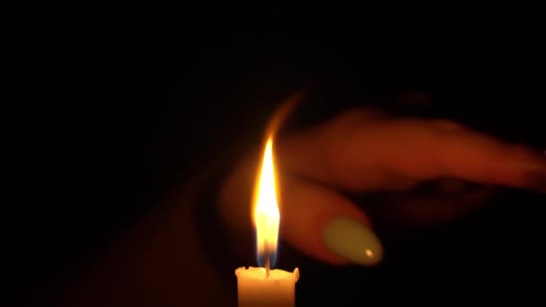 Mujer corre su mano a través de la llama de una vela amarilla — Vídeos de Stock