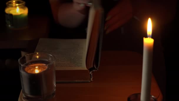Chica lee un libro antiguo a la luz de las velas en la noche — Vídeo de stock