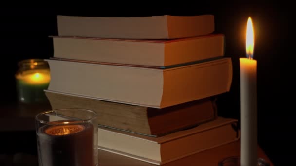 Pila de libros a la luz de las velas, una selección de literatura para leer por la noche — Vídeos de Stock