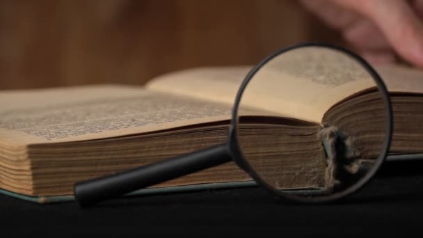 Libro viejo está cerrado por una chica al lado de una lupa — Vídeos de Stock