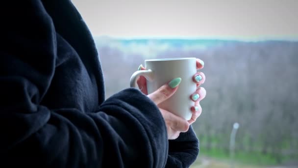 Жінка п'є каву з Кубка в чорному батробі на відкритому вікні вранці — стокове відео