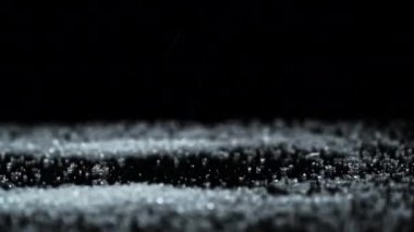 Beyaz Granulated Şeker Siyah Cam bir yüzeye dökülüyor ve bir kaydırak oluşturuyor