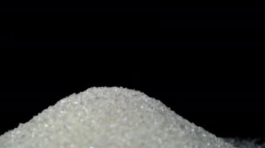 Beyaz Granulated Şeker Siyah Cam bir yüzeye dökülüyor ve bir kaydırak oluşturuyor