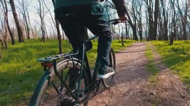 Молодий хлопець їде велосипедом по шляху в зеленому лісі, задній вид у повільному Мо — стокове відео