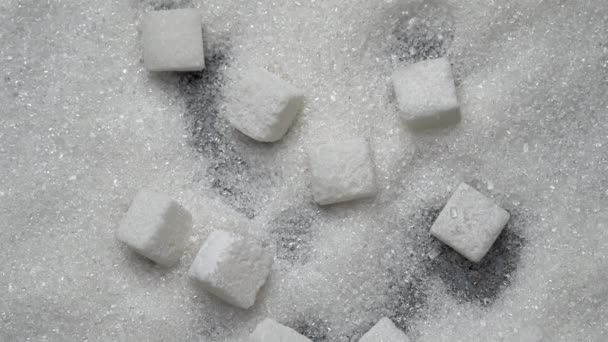 Cubos de azúcar blanco caen sobre el azúcar granulado — Vídeos de Stock