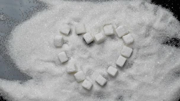 Cubos de azúcar blanco en forma de corazón yacen en la arena de azúcar — Vídeo de stock