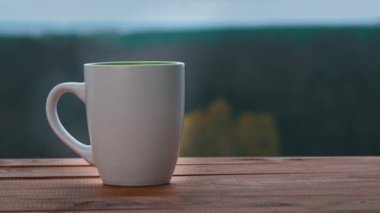 Bir fincan sıcak çay ya da kahve Açık Pencere kenarında durur ve buhar çıkarır.