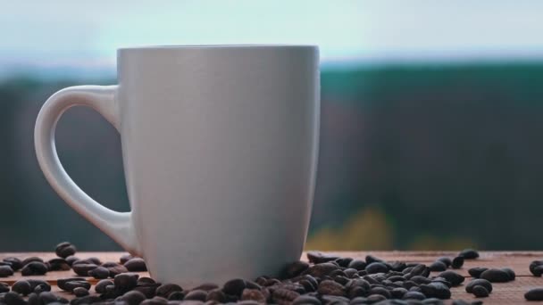 Coupe de café chaud se tient près de la fenêtre ouverte et libère de la vapeur contre le ciel — Video