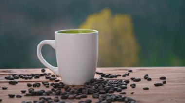 Bir fincan sıcak kahve pencerenin yanında durur, Buhar çıkarır ve kaşıkla şeker koyar.