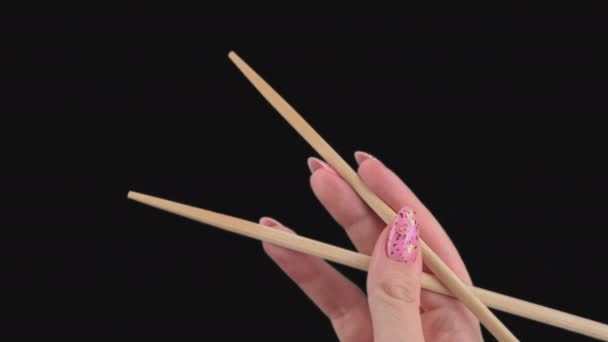 Las manos femeninas sostienen palillos japoneses para rollos de sushi sobre un fondo transparente — Vídeo de stock