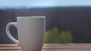Bir fincan sıcak çay ya da kahve Açık Pencere kenarında durur ve buhar çıkarır.