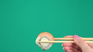 Kadın Elleri Japon Yemek Çubuklarını Yeşil Arkaplanda Suşi Yuvarlamalarıyla Tutar