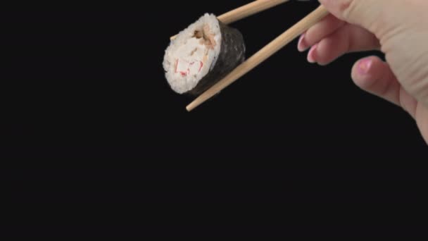 Kvinnliga händer hålla japanska ätpinnar med sushi rullar på transparent bakgrund — Stockvideo