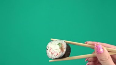 Kadın Elleri Japon Yemek Çubuklarını Yeşil Arkaplanda Suşi Yuvarlamalarıyla Tutar