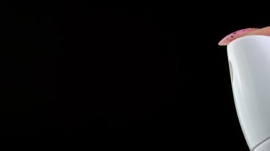 Pressing a Button on White Deodorant Spray with Jet Stream on a Black Background